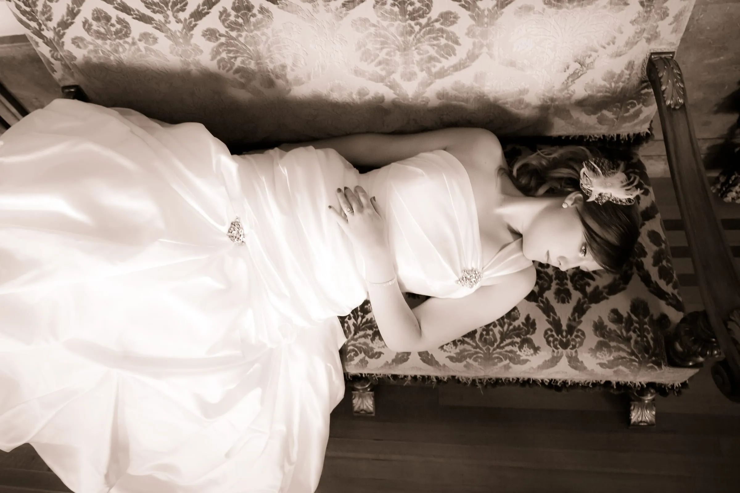 Black-and-white portrait of a bride reclining on a vintage sofa