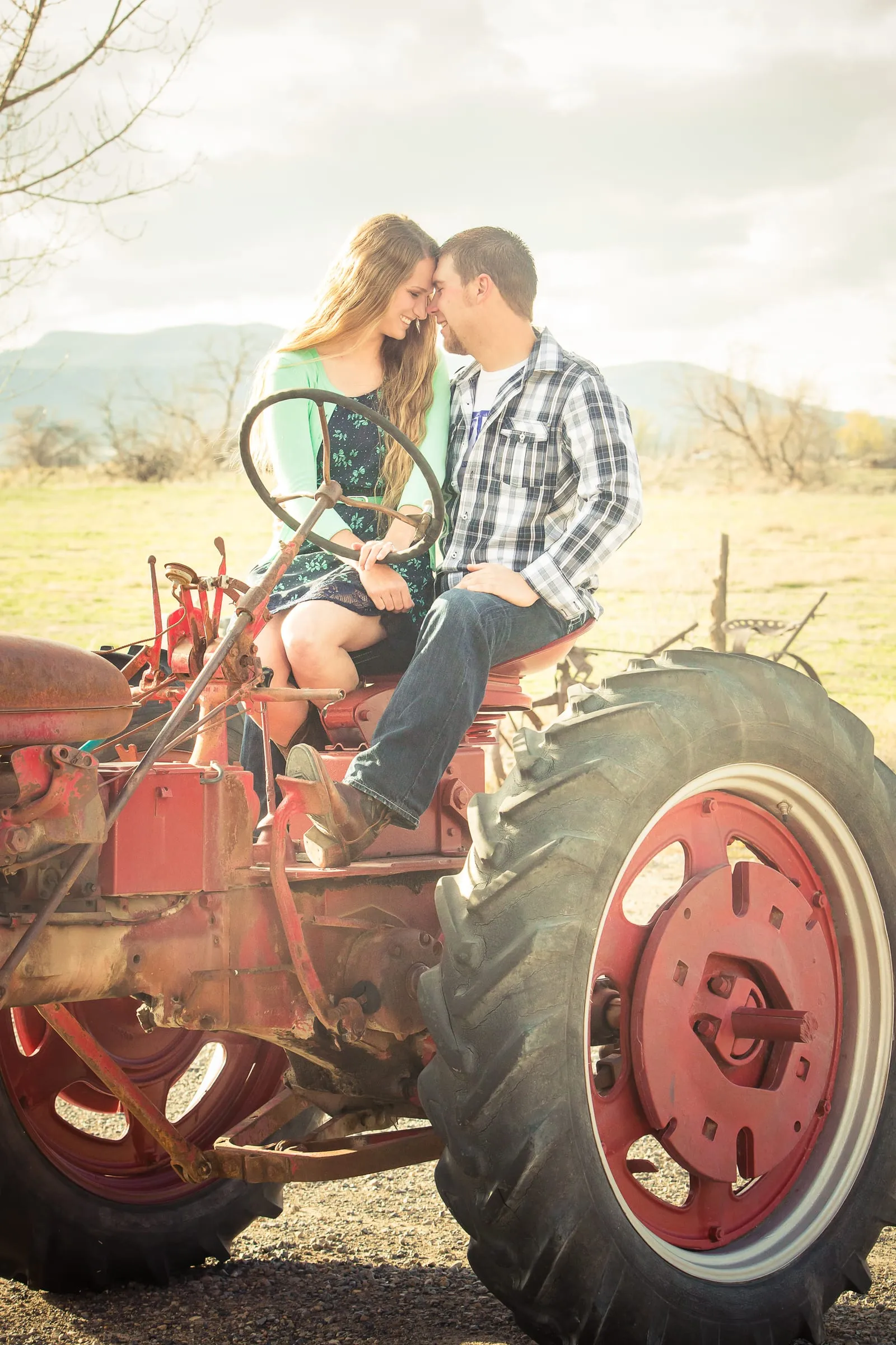 Couple sitting together on a vintage red tractor in a field