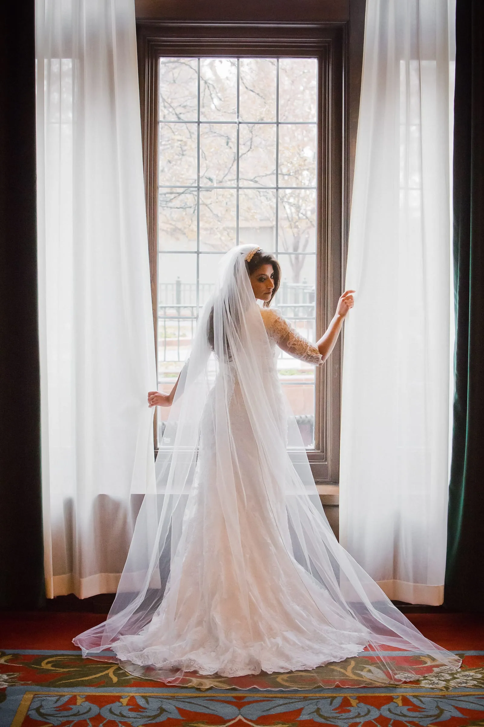 Bride with a long veil glowing in window light
