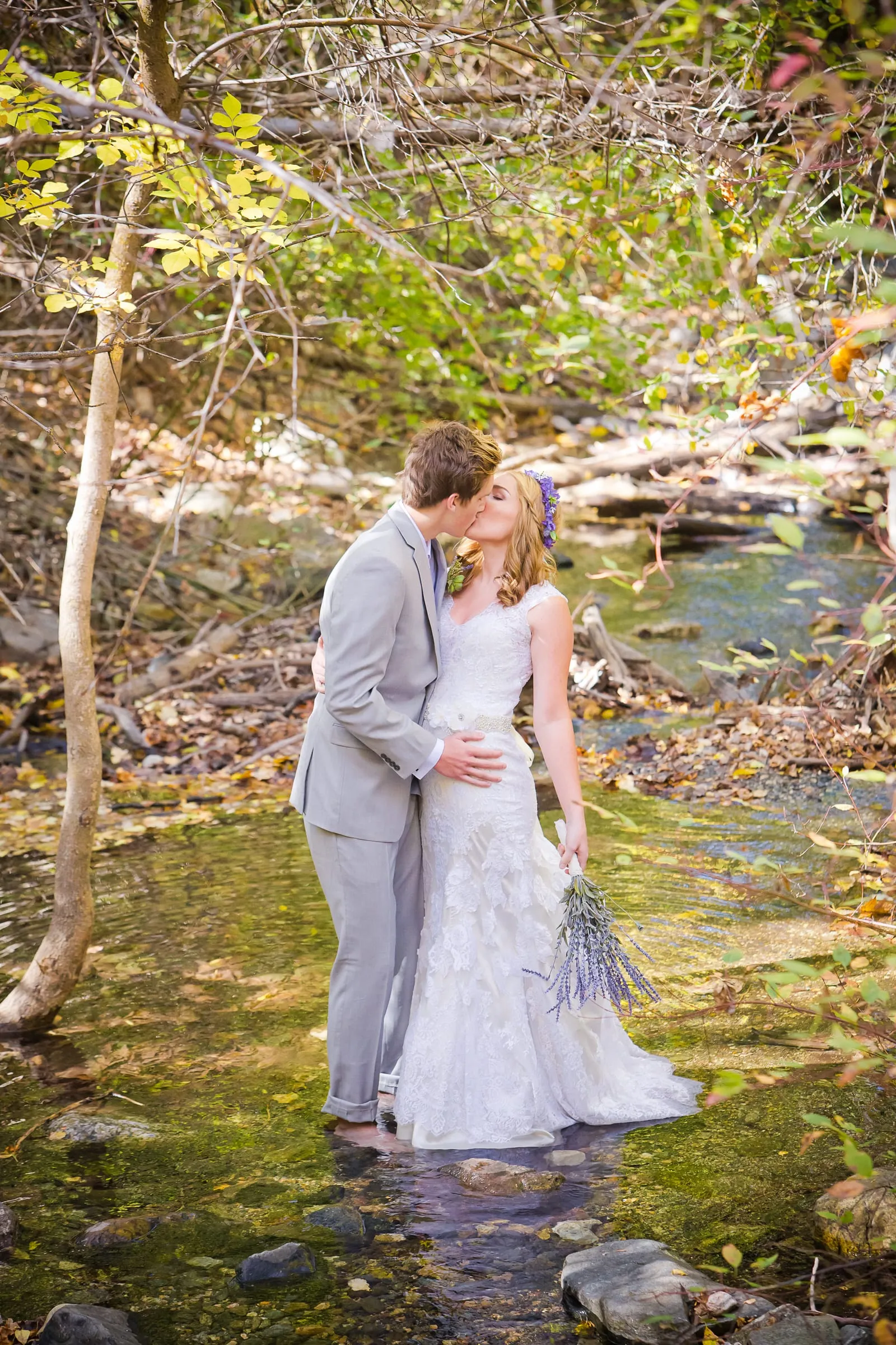 Bride and groom standing in a mountain stream surrounded by trees
