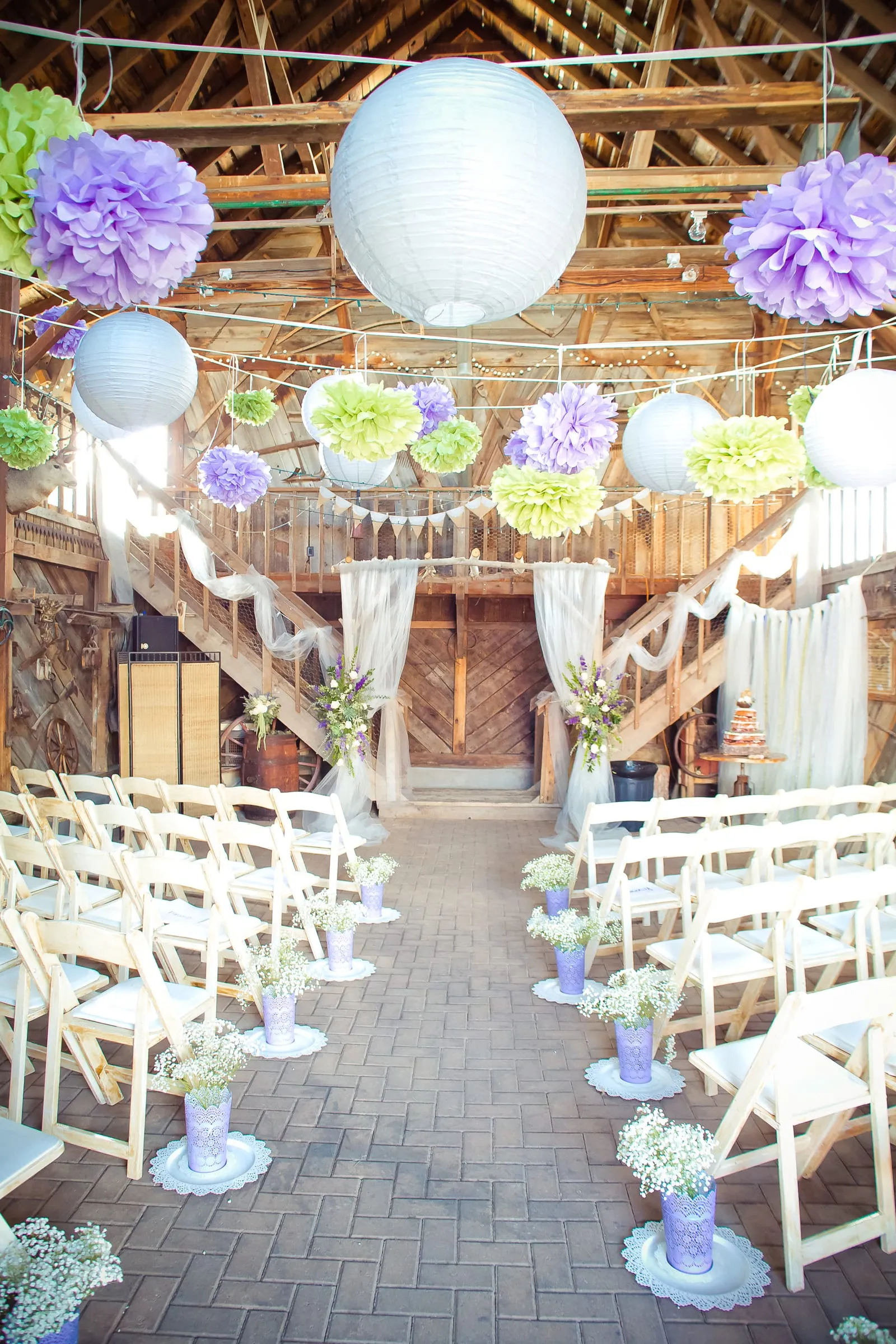 Outdoor ceremony setup with white chairs and hanging paper lanterns