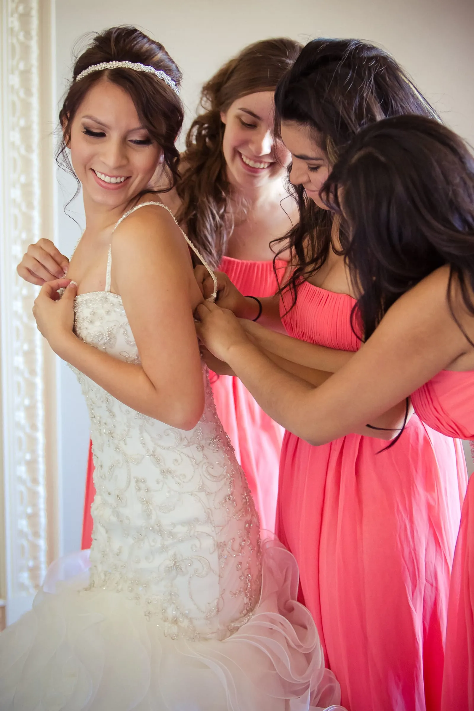 Bride laughing with her bridesmaids in coral dresses