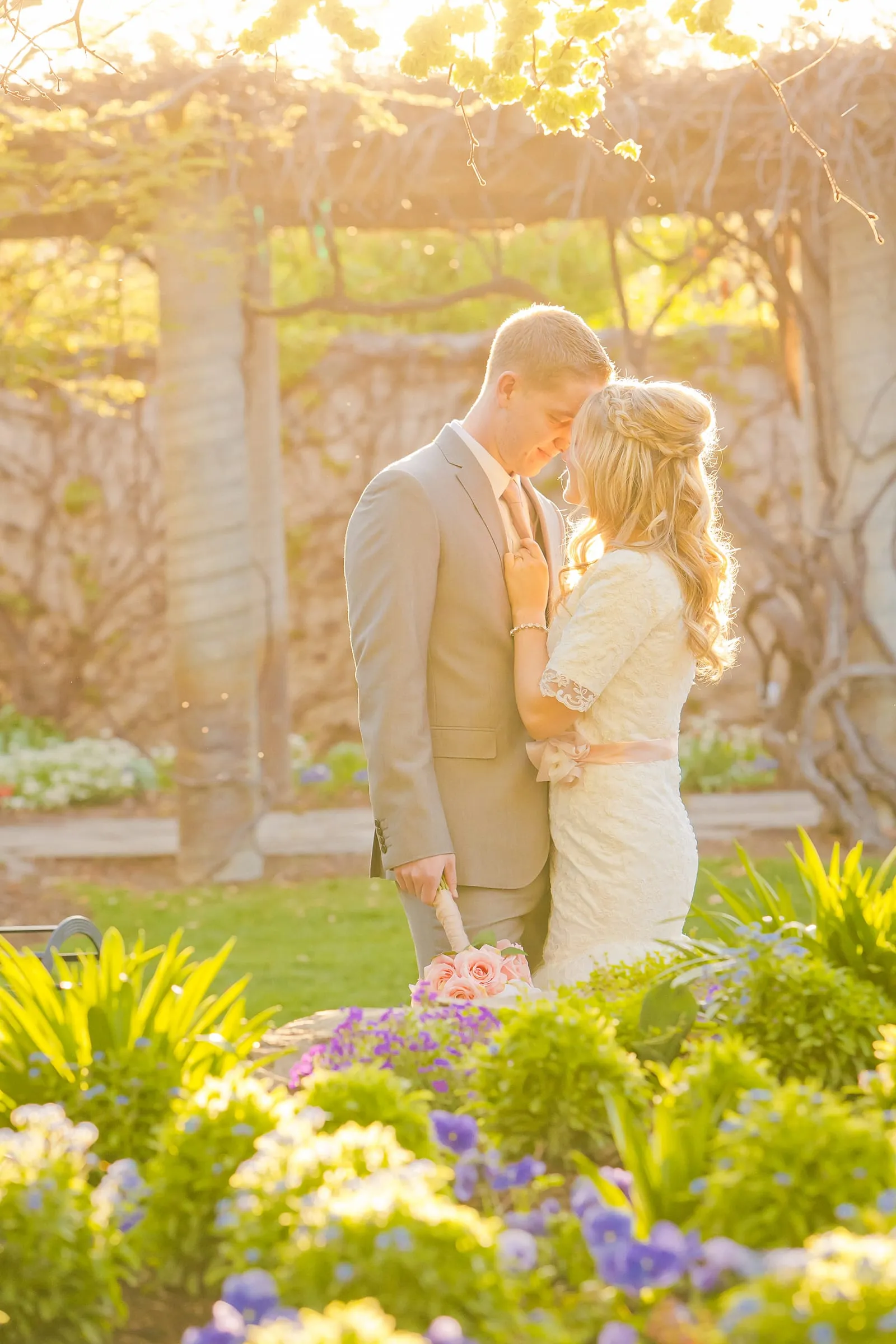 Bride and groom under a garden arbor surrounded by flowers