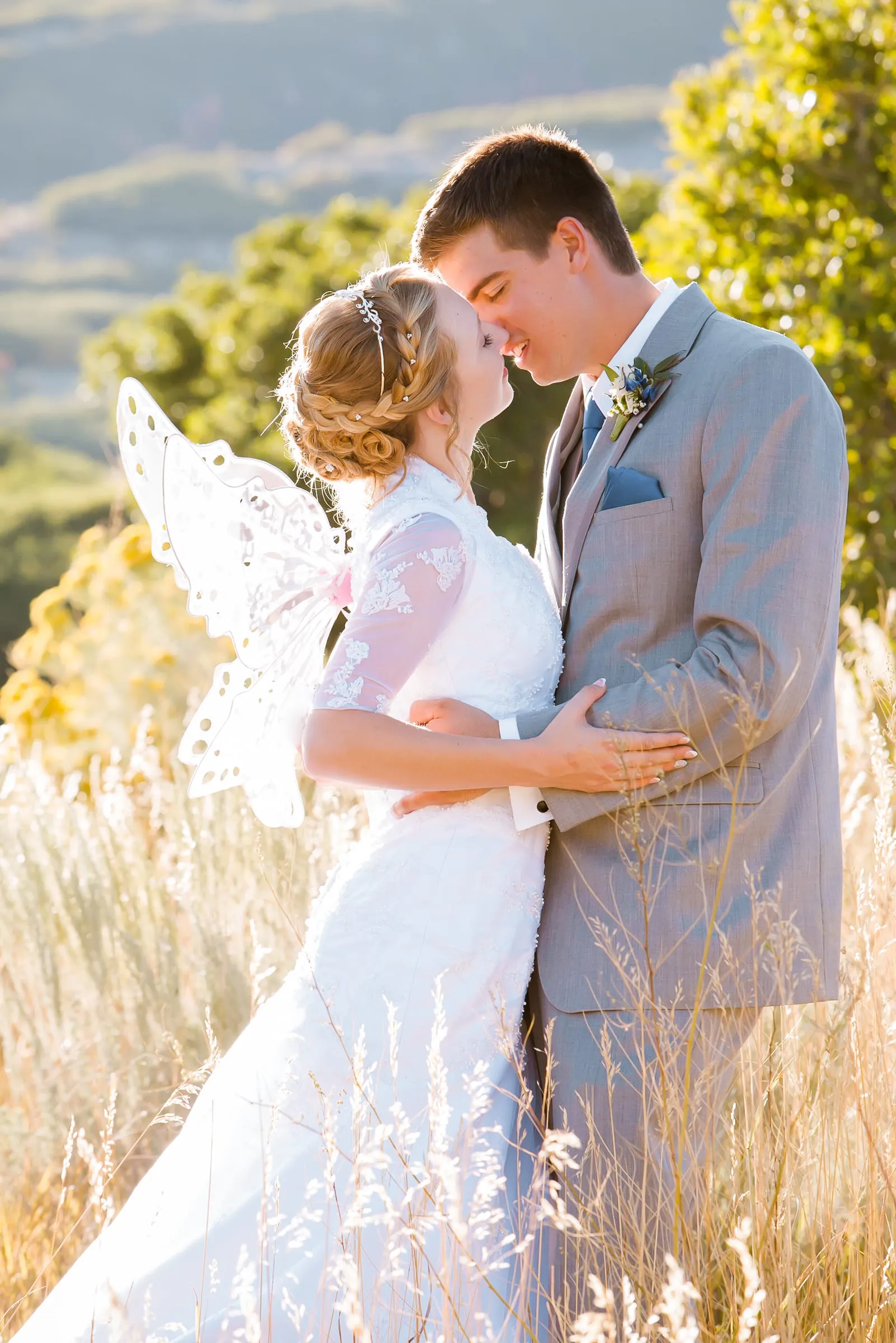 Bride and groom embracing in golden grass at the end of the day