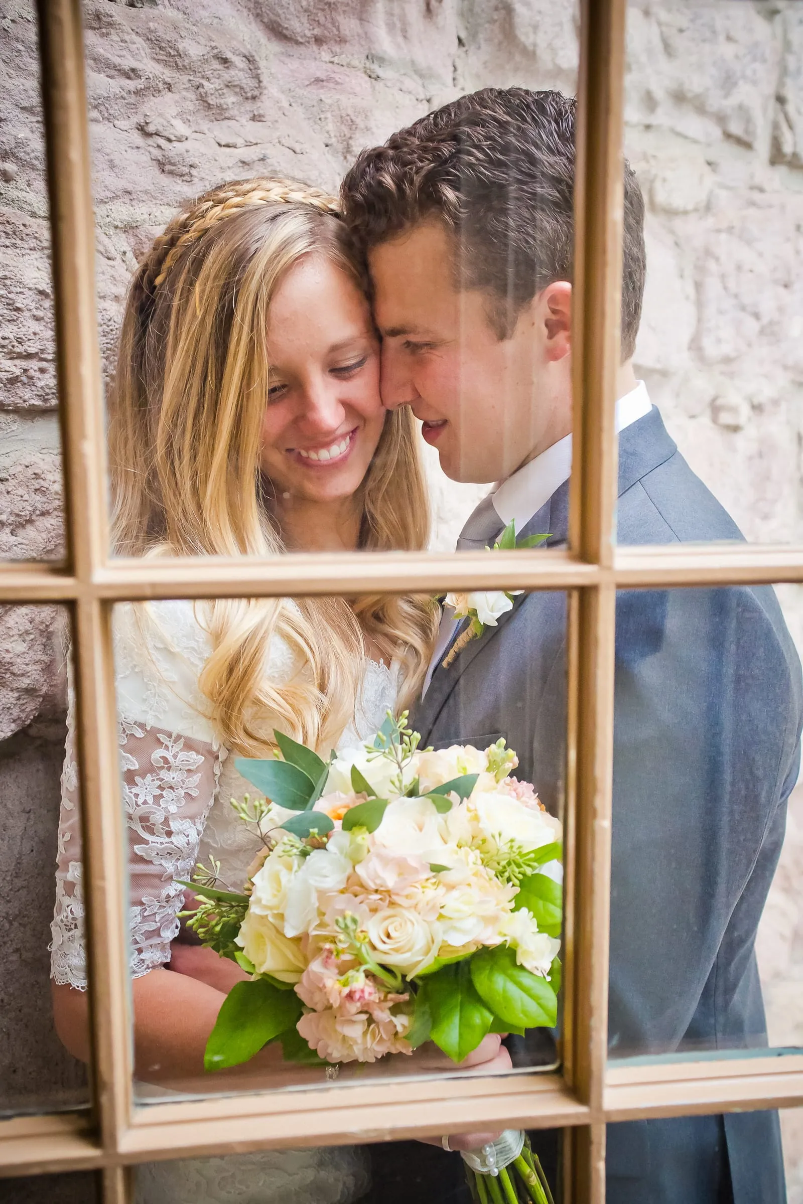 Bride and groom seen through old window panes, holding a bouquet