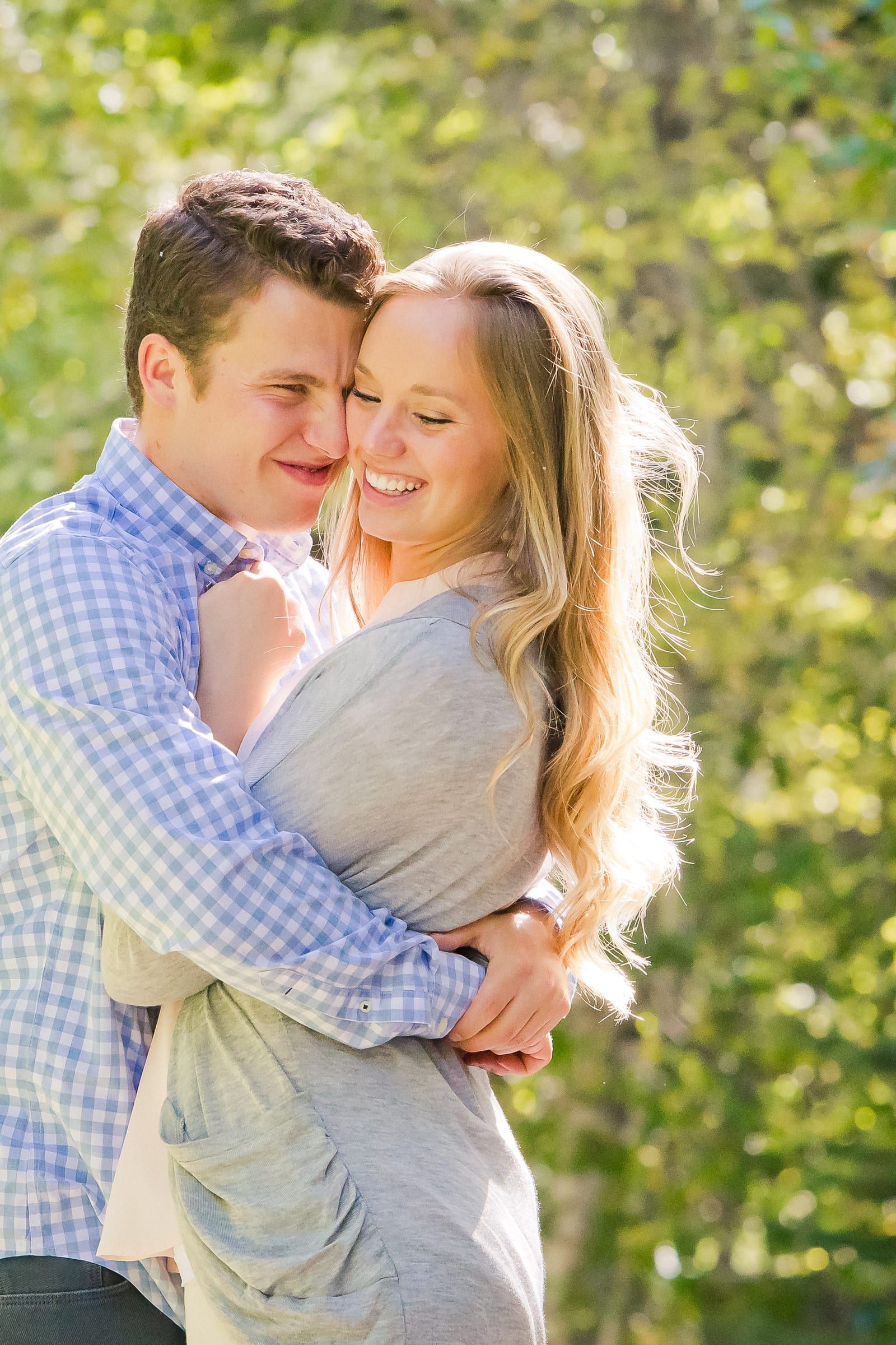 Couple hugging and laughing among green trees