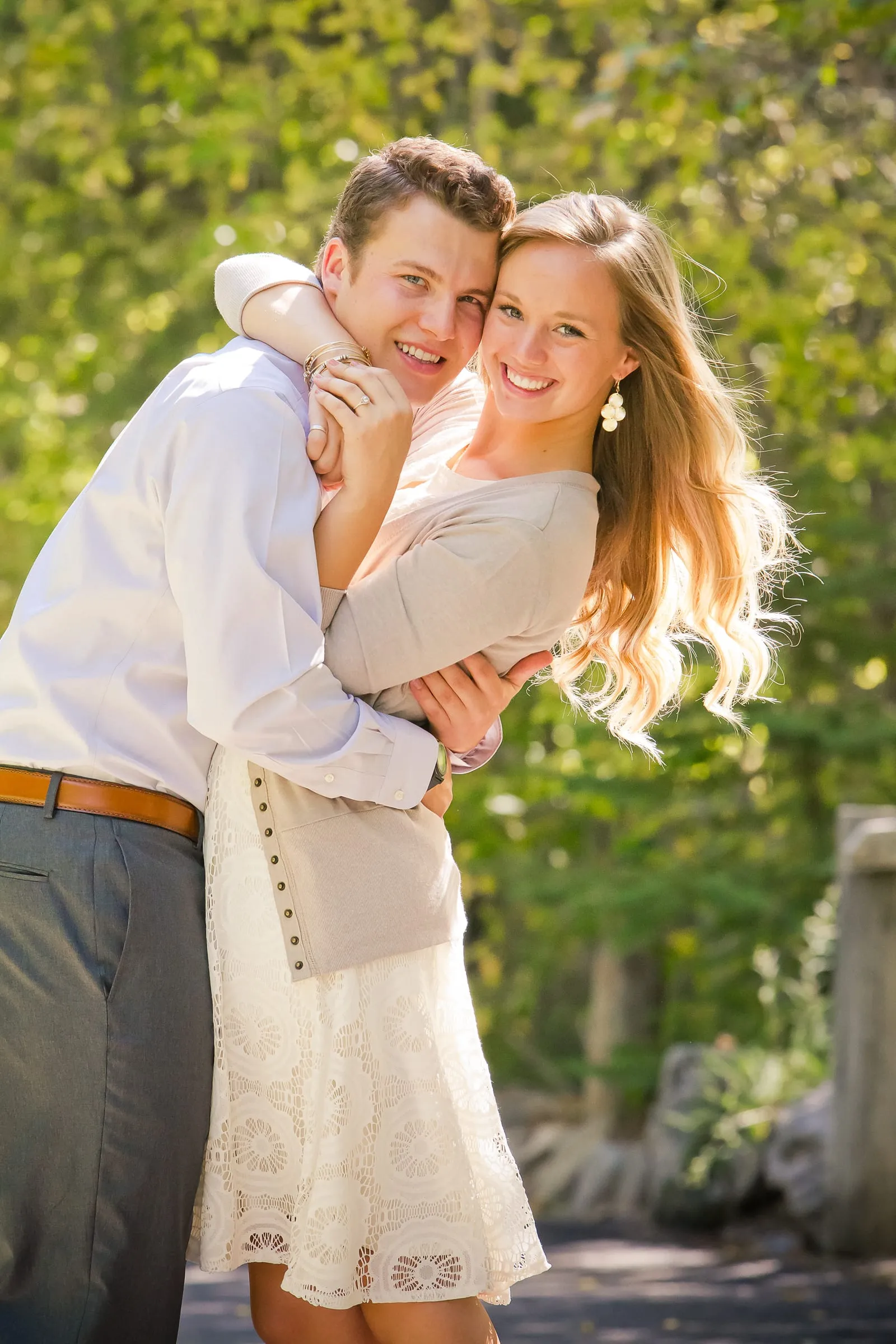 Woman jumping into her fiancé's arms on a garden path