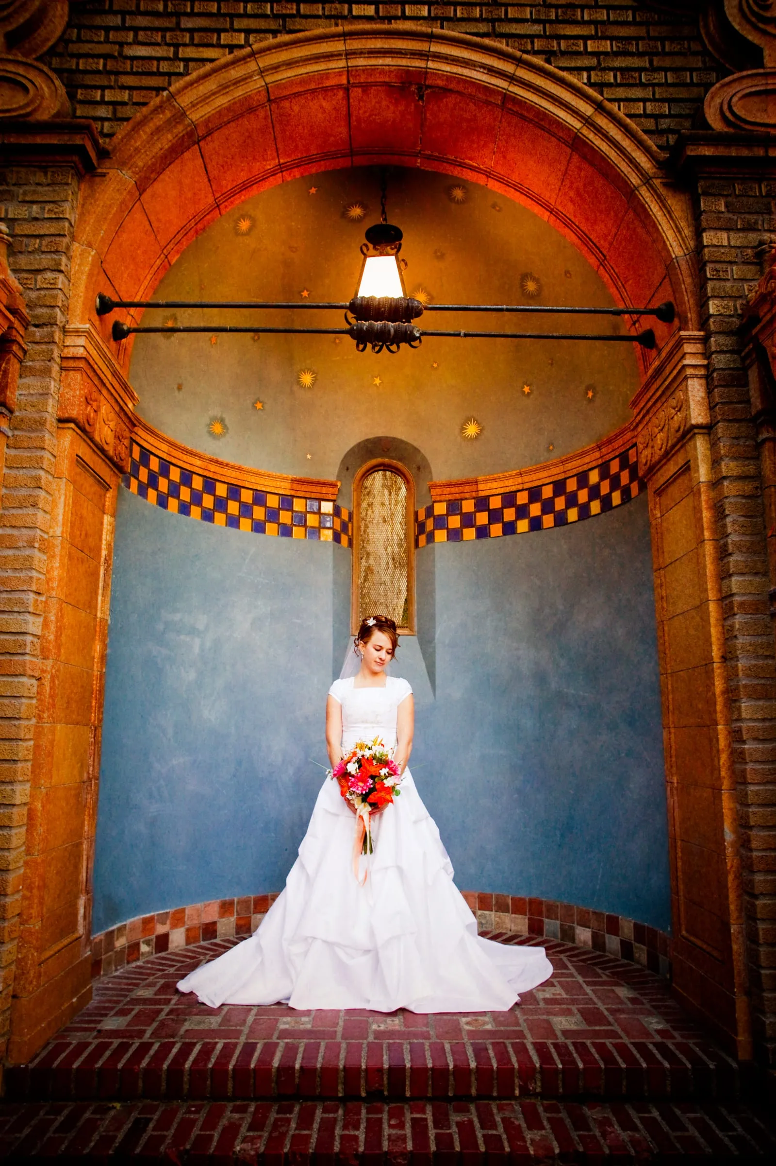 Bride beneath a lantern-lit arched brick alcove