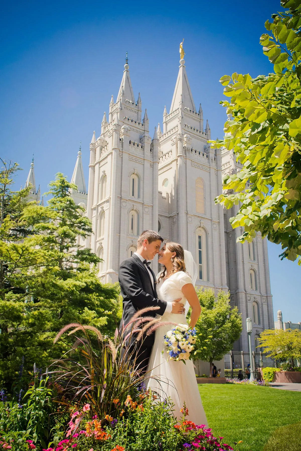 Bride and groom on temple grounds with the temple spires rising behind them