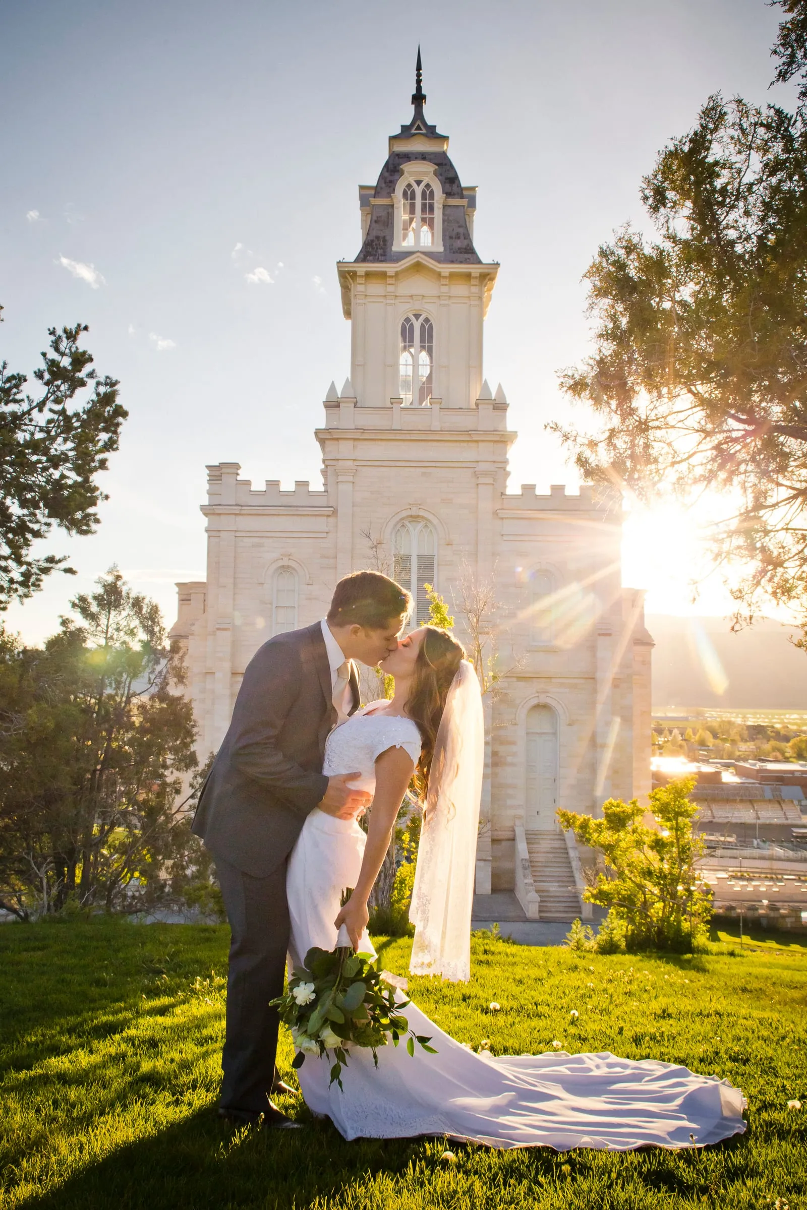 Bride and groom kissing on a temple lawn on a sunny afternoon