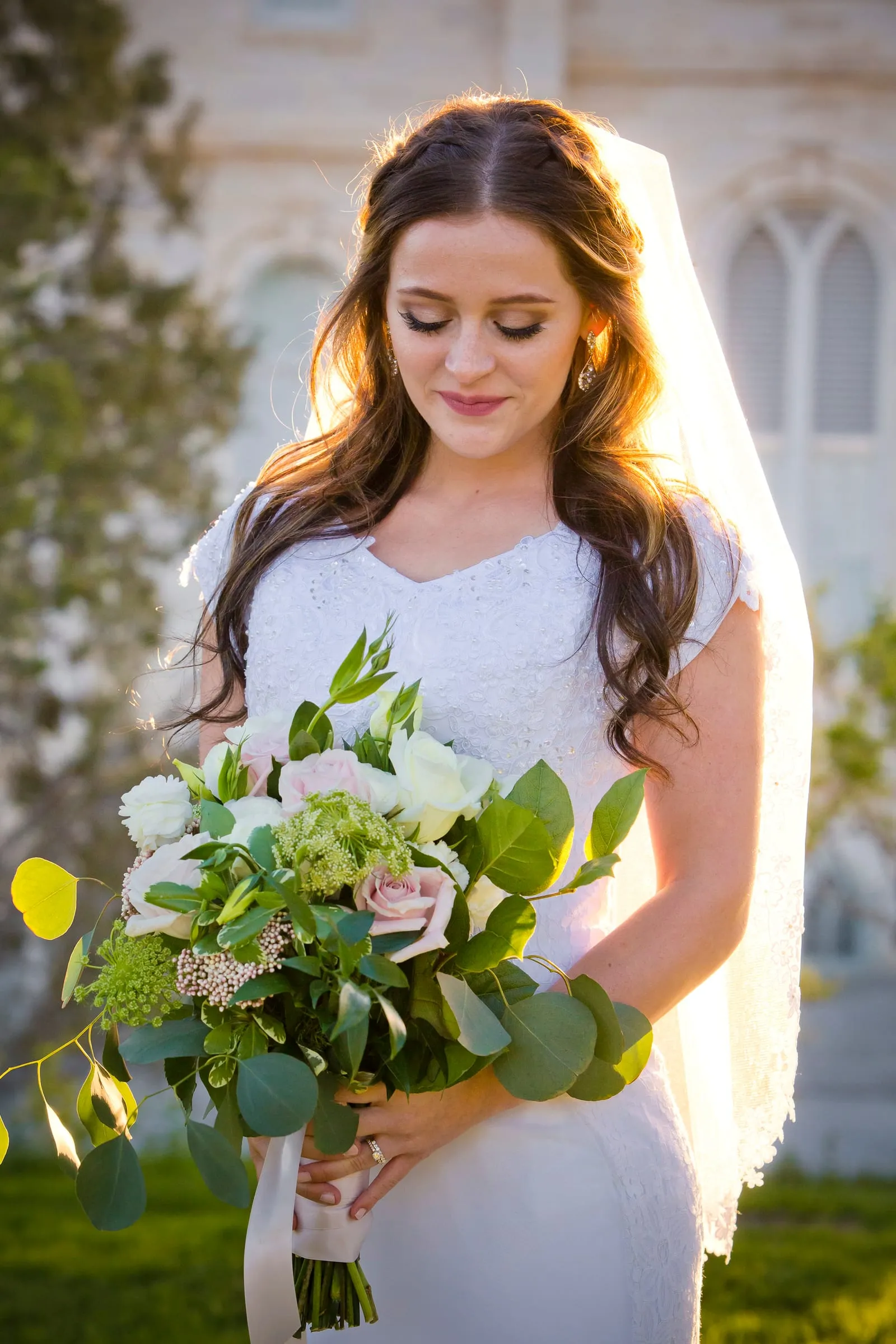 Bride holding her bouquet with a white temple behind her