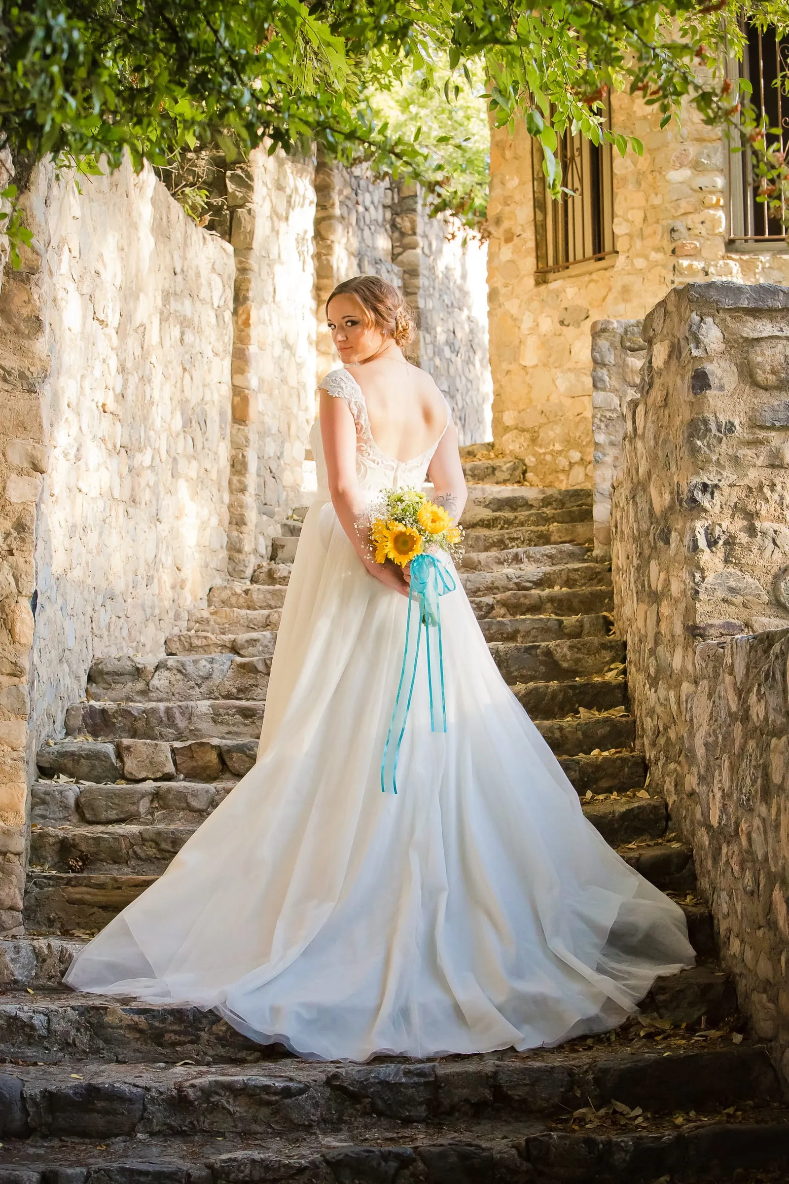 Bride on a stone staircase draped with greenery