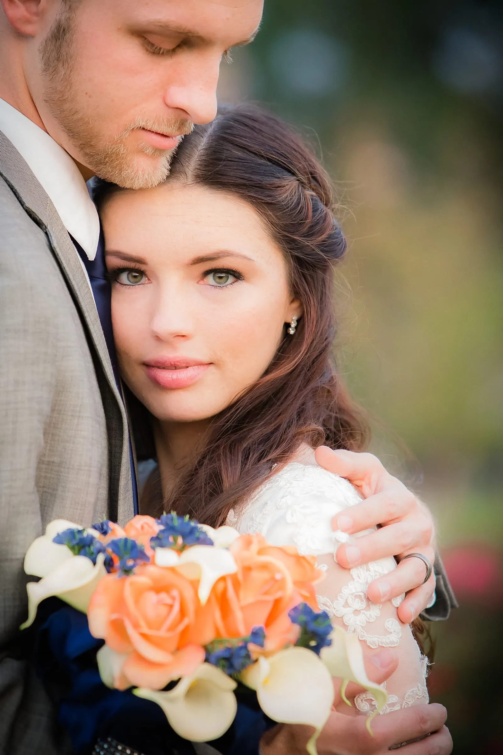Couple close together with an orange and blue bouquet