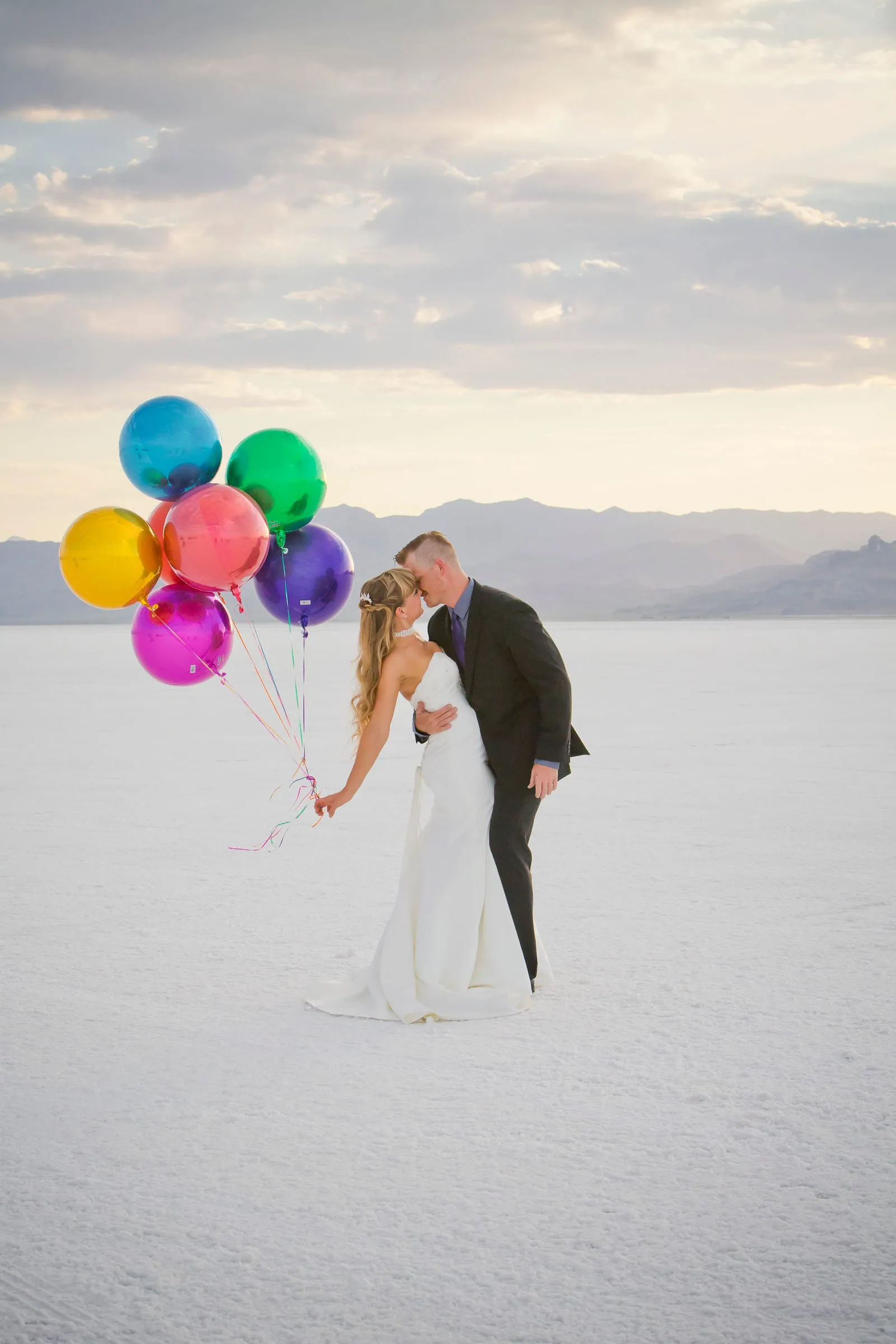Bride and groom holding colorful balloons on wide open salt flats