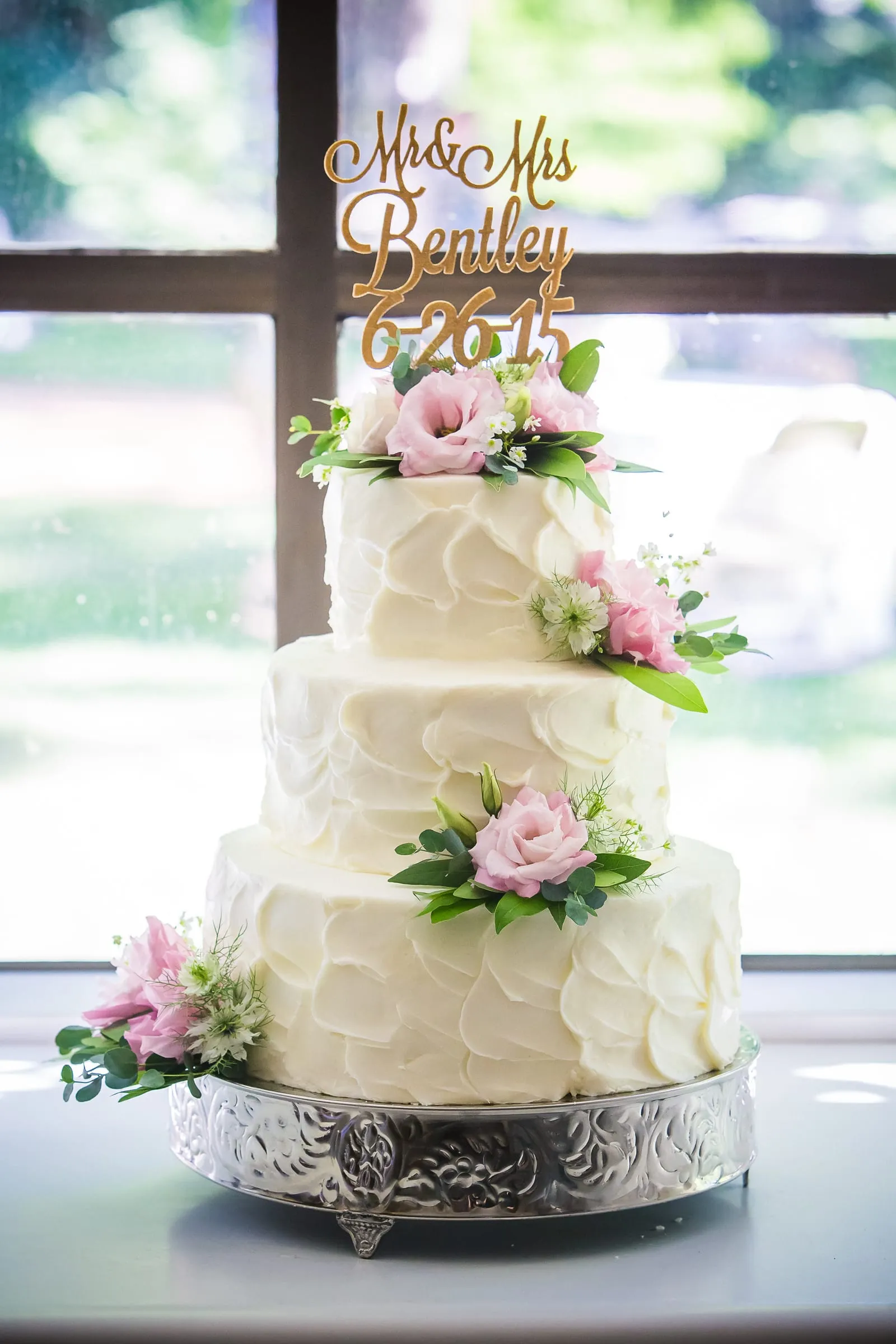 Tiered white wedding cake with a script cake topper
