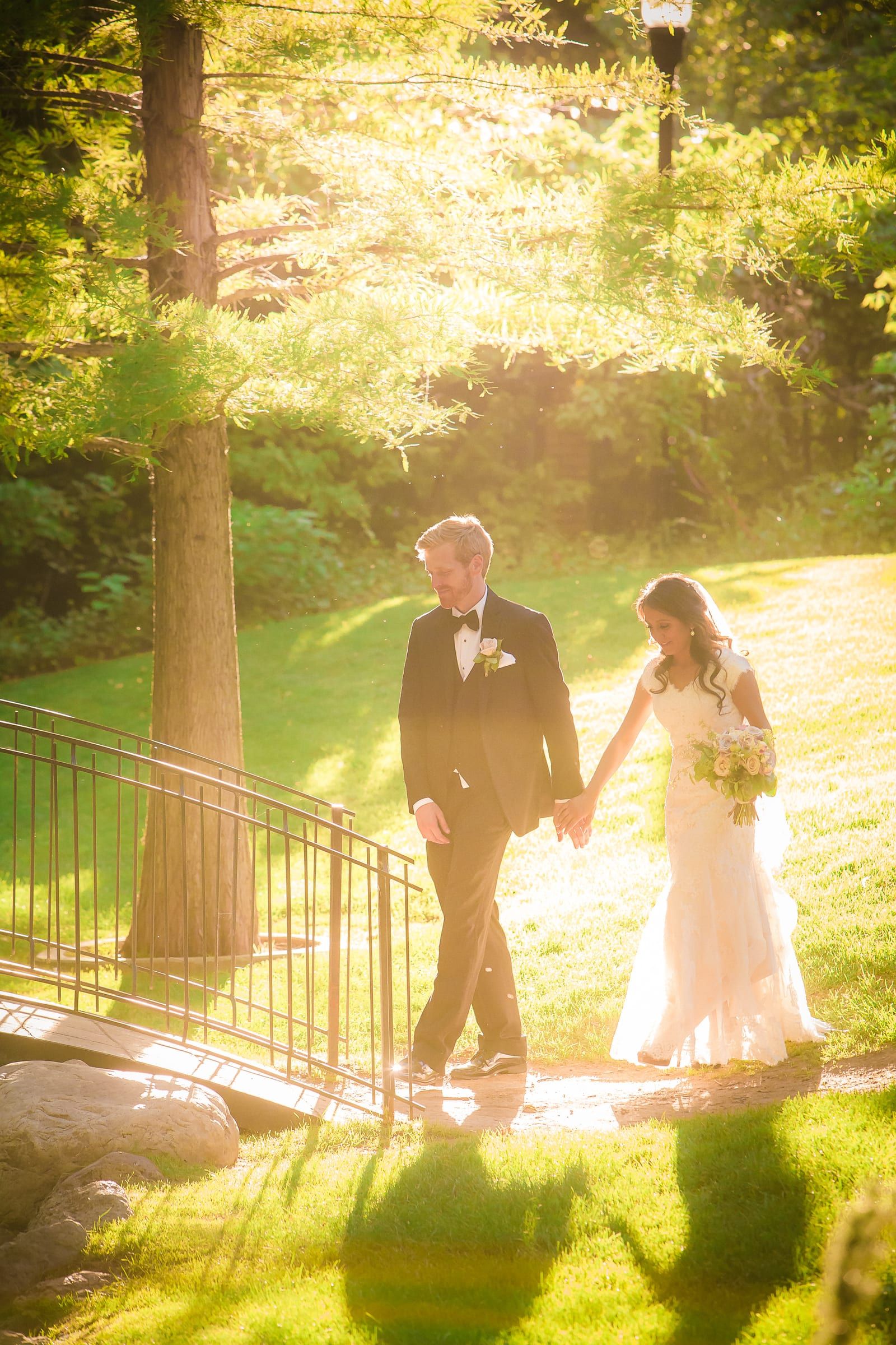Bride and groom walking through a sunlit garden