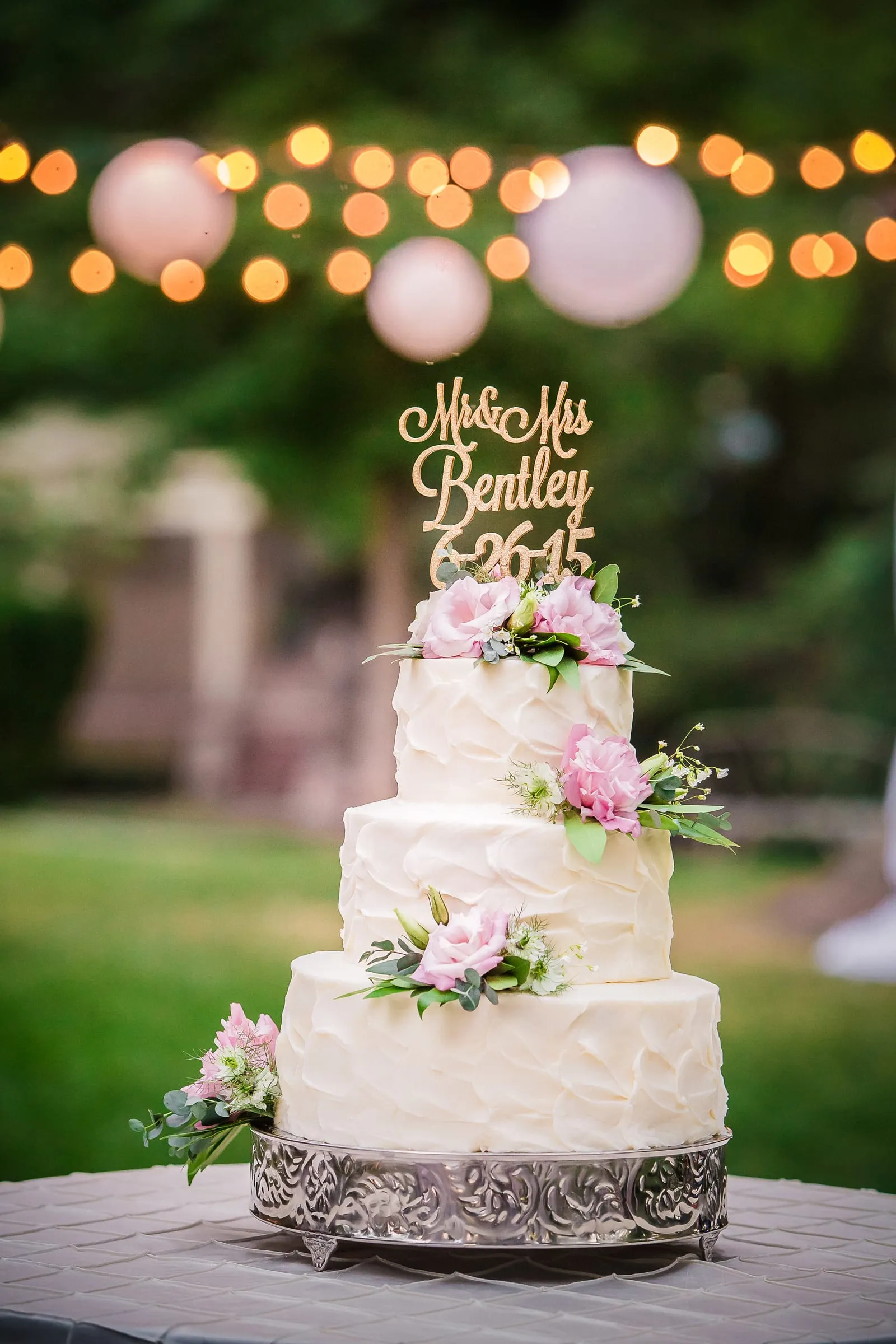 Wedding cake glowing under outdoor string lights