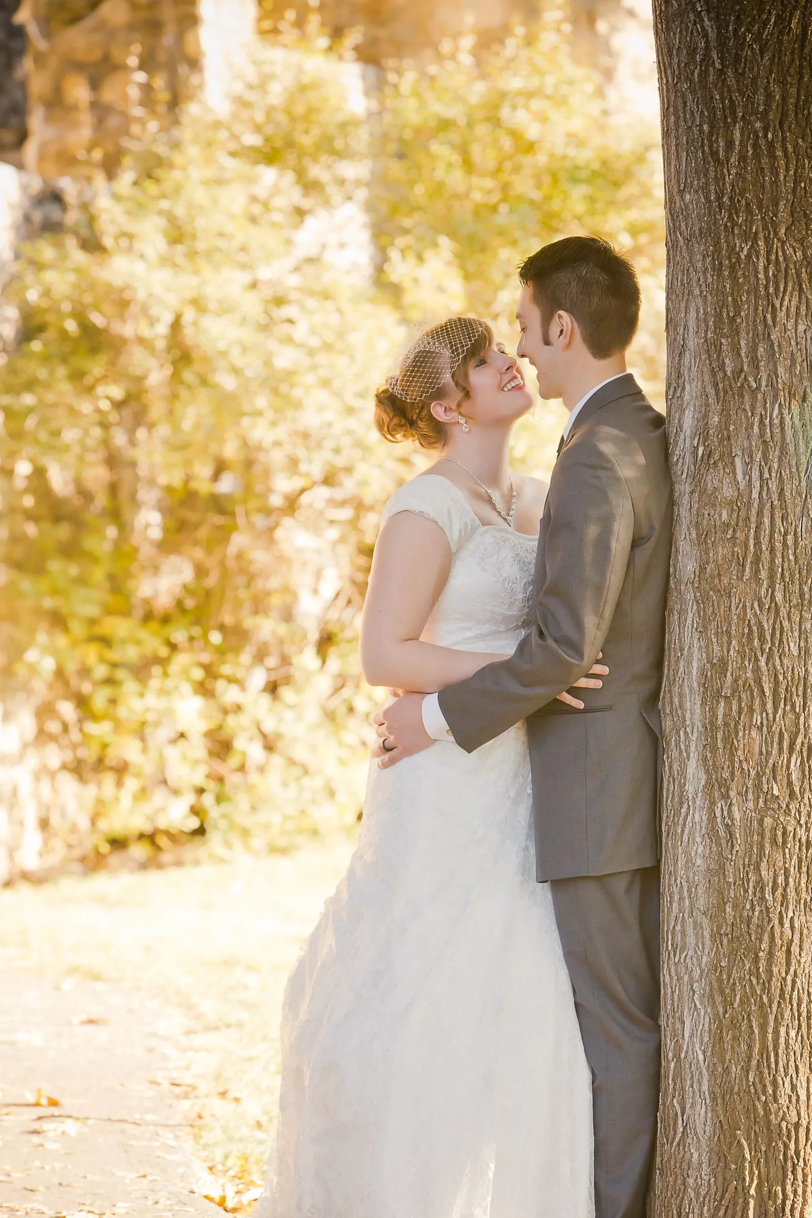 Bride and groom kissing beside a large tree trunk
